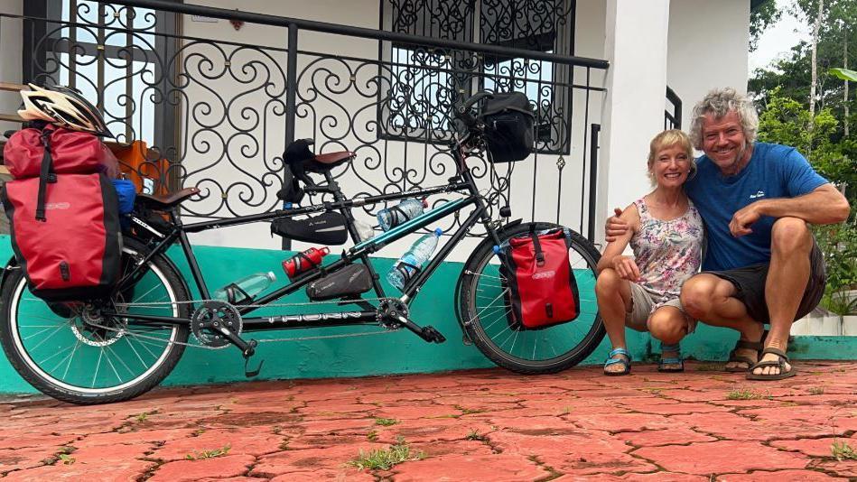 Dave and Helen crouch for a photo by their bike 