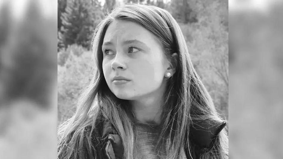 A black and white image of a young girl with her hair down looking to the right of the shot. 