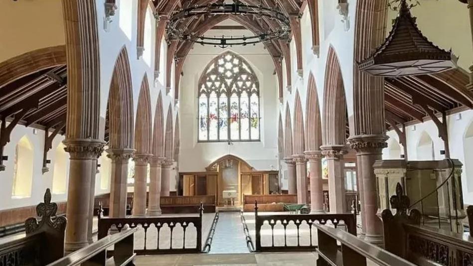 The interior of Cathedral Isle of Man after the removal of most of the pews for refurbishment works. The tall building has a large stained glass window above the alter.