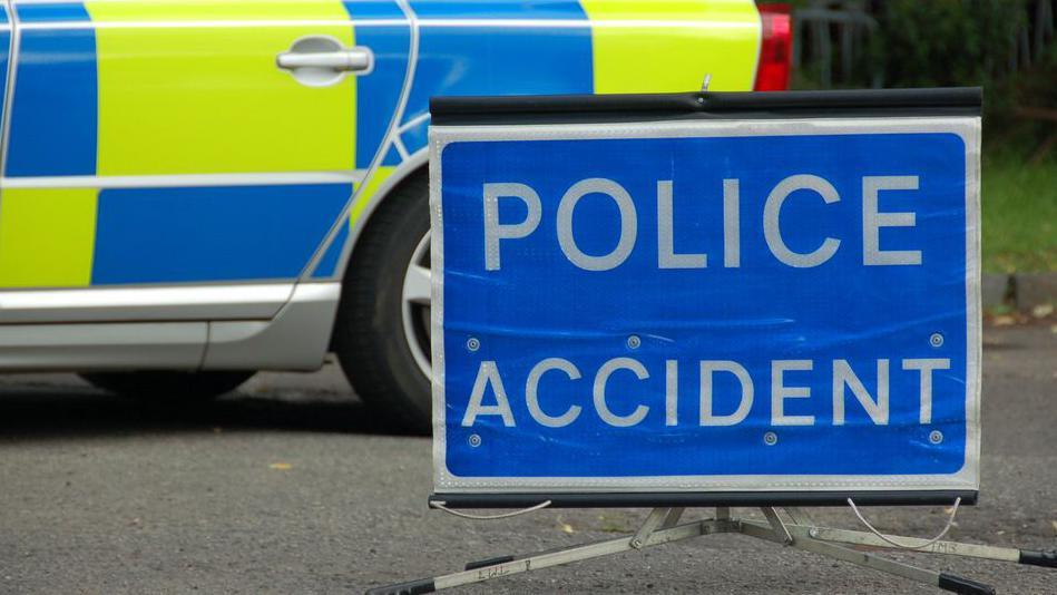 Blue police accident sign with white writing next to the blue and yellow door of a police car 