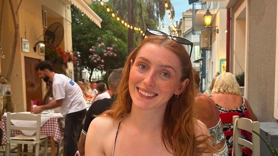 Martha is smiling while sitting at an outdoor restaurant table.