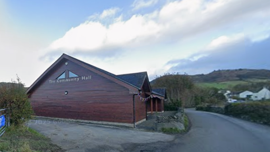 Grizebeck Community Hall on the A595. It is a wooden building which faces out onto the A595 in Cumbria.