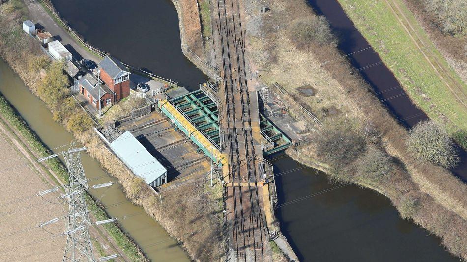 Aerial view of train tracks going across a bridge, which sits above a waterway