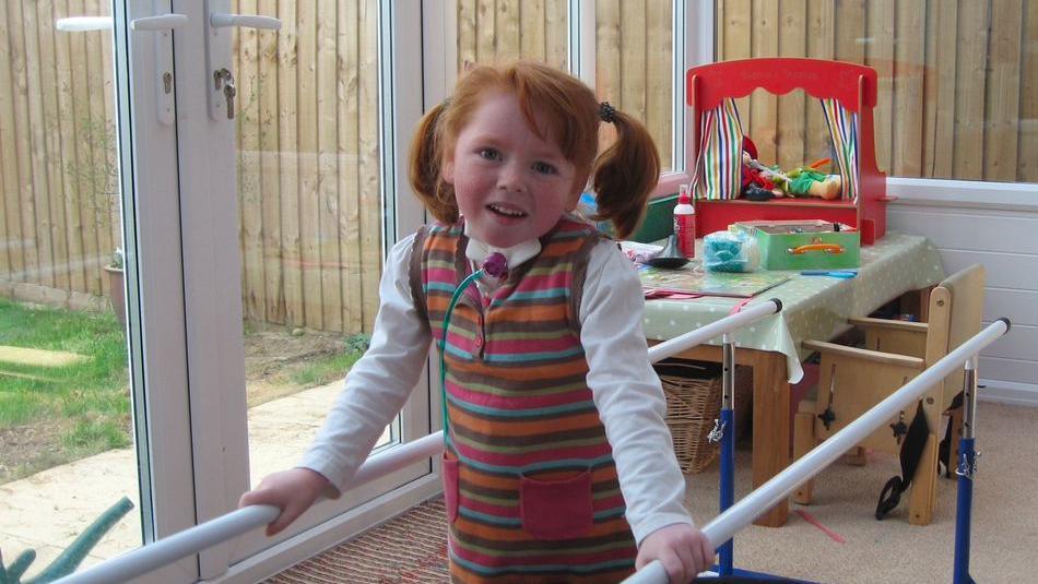 A young girl with ginger hair wearing a striped jumper dress