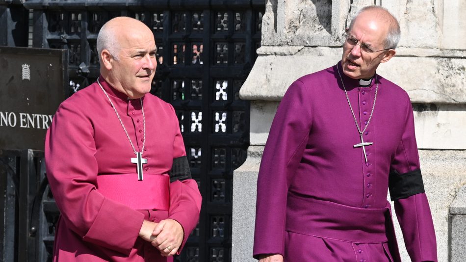 Archbishop of York Stephen Geoffrey Cottrell (left) and The Archbishop of Canterbury Justin Welby outside Westminster Hall, London. They are wearing robes and have a cross hanging around each of their necks.
