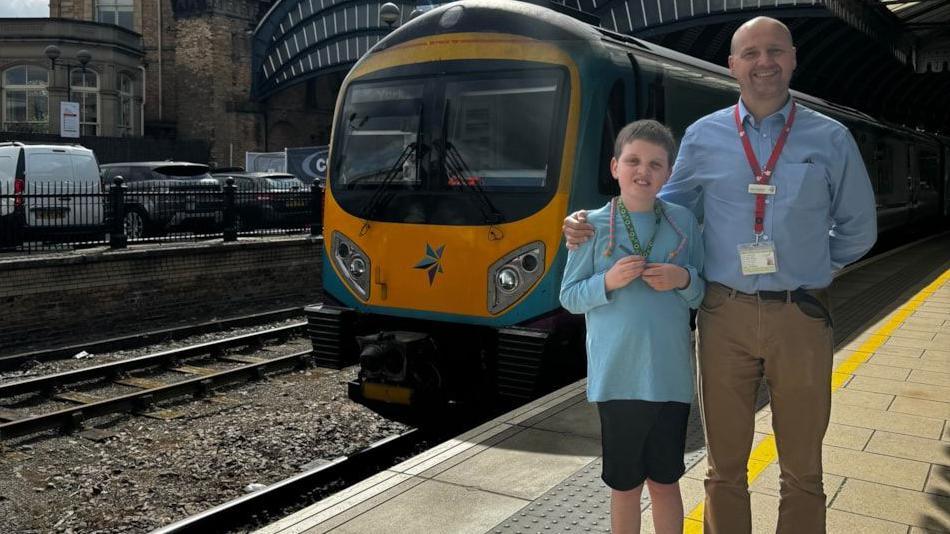 Nathaniel Briggs with Lead Driver Manager Steve Whitehead standing on a train platform in front of a train 