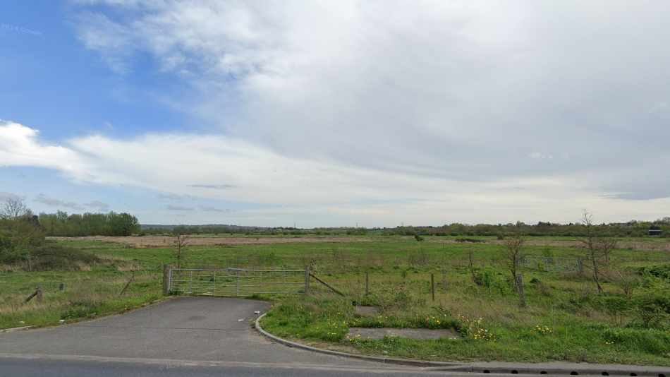 An empty grass plain with a gate and path in the foreground