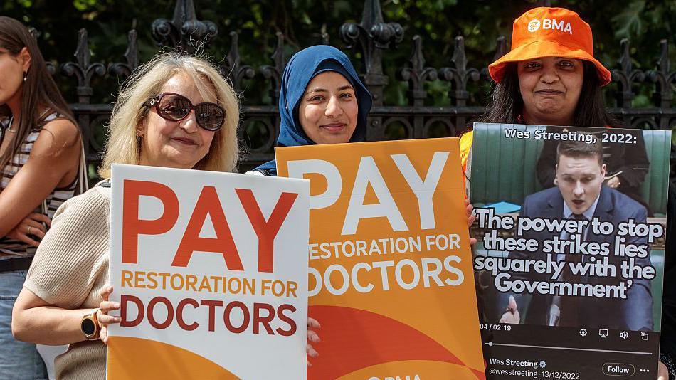 Resident doctors represented by the British Medical Association stand holding signs saying "pay restoration for doctors" on a picket line outside St Thomas' Hospital in London.