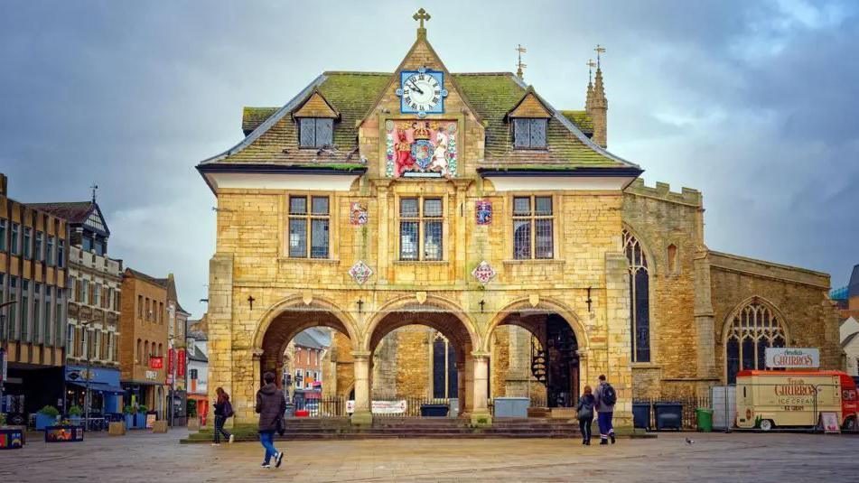 Historic building of the Guildhall in Cathedral Square with people walking in front of it in the square