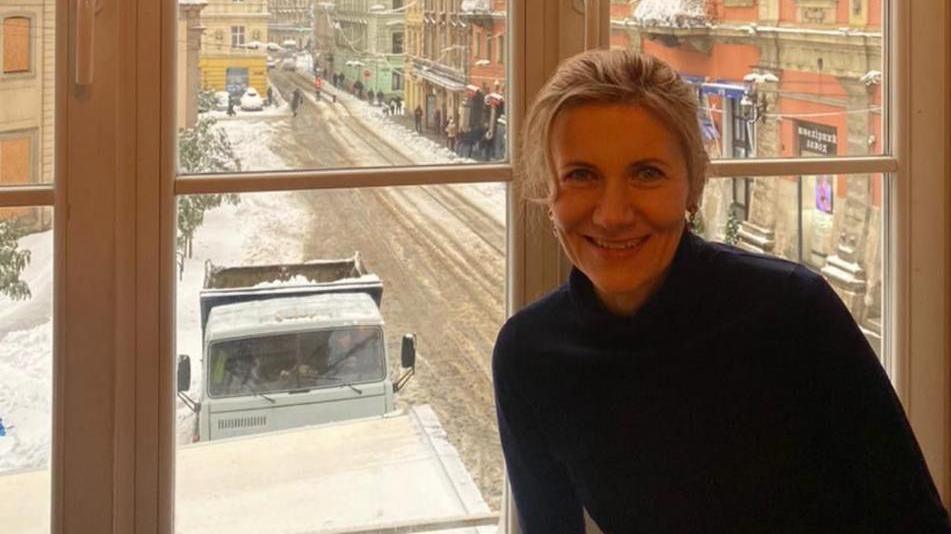 A picture of Natalia Polischuk pictured in front of a window in Lyiv. There is snow on the road and to the side of it in the background.