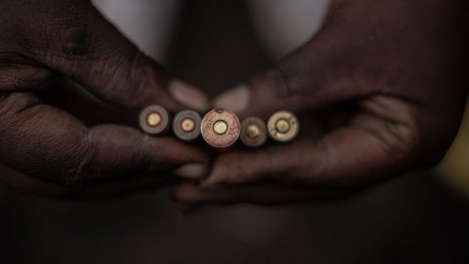 A close up of a pair of hands holding five bullets.