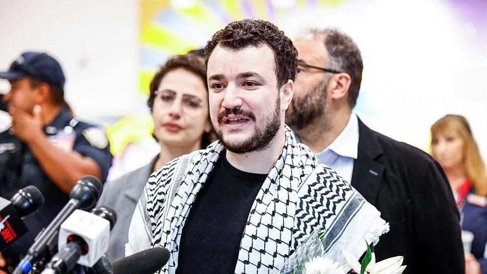 Mahmoud Khalil with a Palestinian keffiyeh around his shoulders speaking at an event