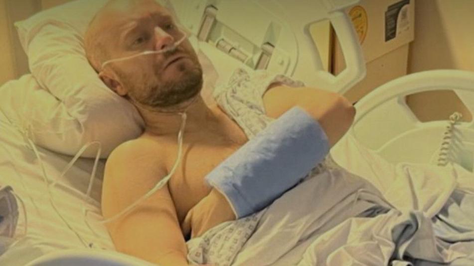 Jamie Lonsdale in his hospital bed surrounded by tubes