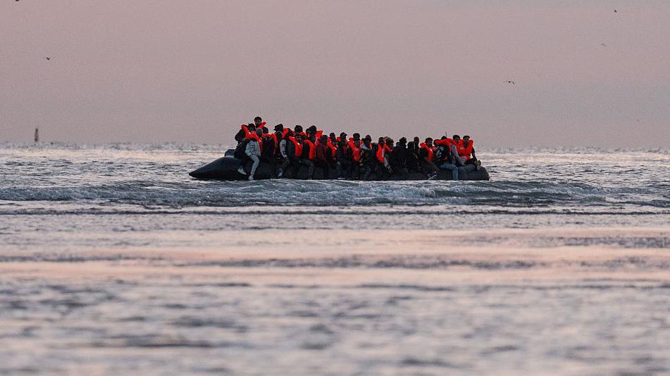 Migrants sit on a dinghy as it prepares to sail into the English Channel on 10 July 2025 in Gravelines, France.