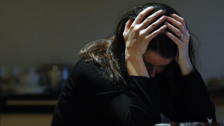 A woman with her head in her hands and a blurred background