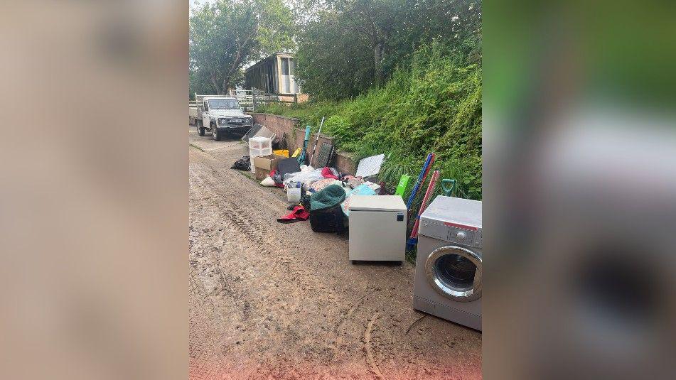 A washing machine and other items of equipment are lined up on a path.