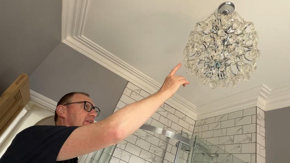 Rob Wilson points at a chandelier. 