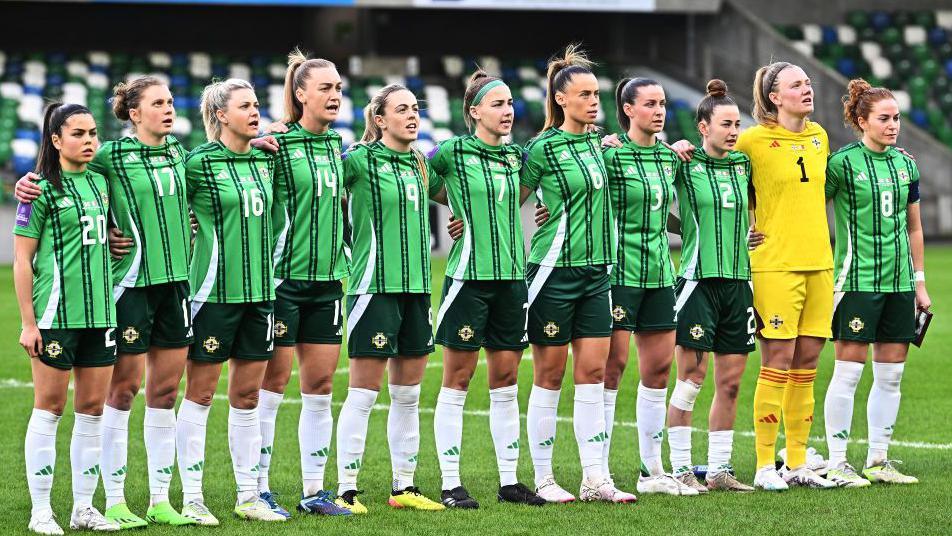 The Northern Ireland squad link arms during the national anthem before a match.