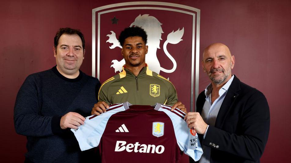 Marcus Rashford holding up an Aston Villa shirt