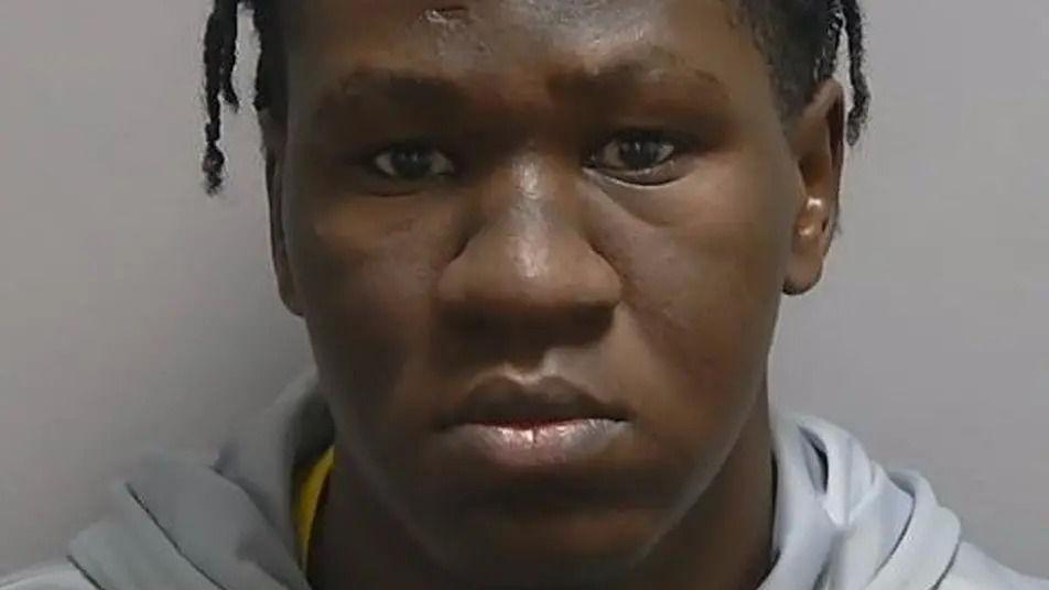 A close up picture of Sudanese man's face posing for a police mug shot.