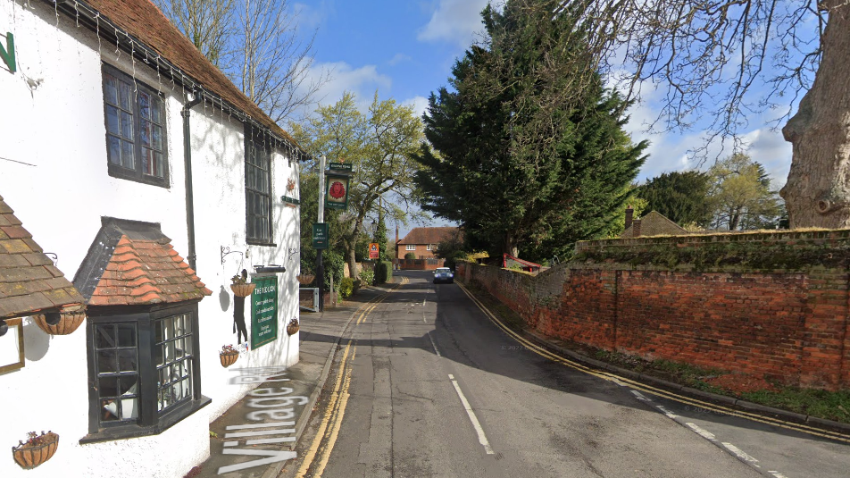 Village Road on streetview, showing a white pub, a narrow road and a red brick wall