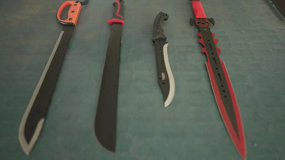 Four, large knives are laid out on a table.