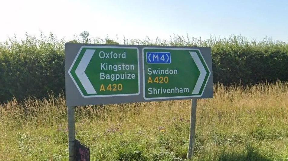 Road signs: on the left pointing to Oxford and Kingston Bagpuize, on the right Swindon and Shrivenham.