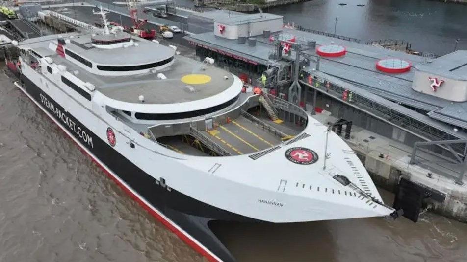 The fast craft Manannan docked in the Liverpool ferry terminal. It is a catamaran in white, black and red with Steam-Packet.com on the side.