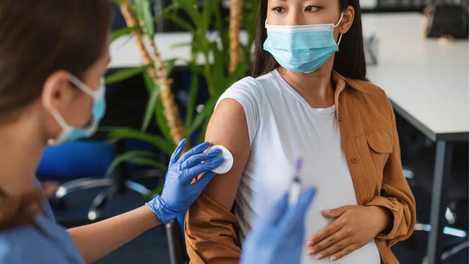 Pregnant woman receiving injection from nurse (generic image)