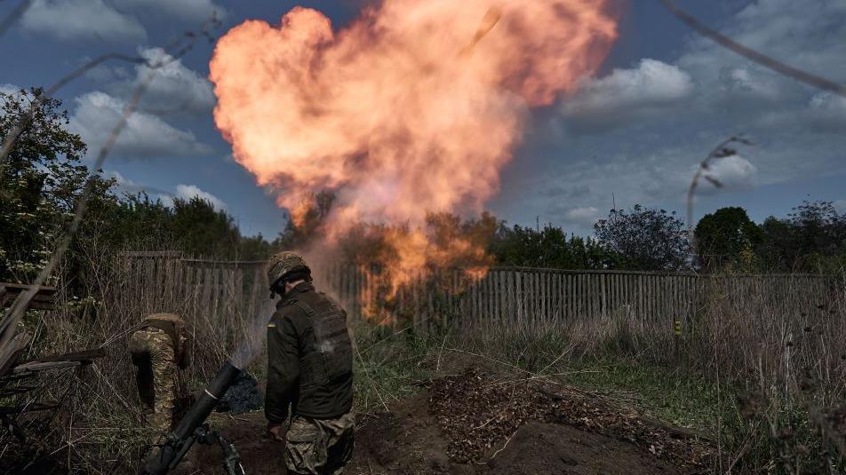 Ukrainian soldiers fire a mortar as flames erupt from its tube