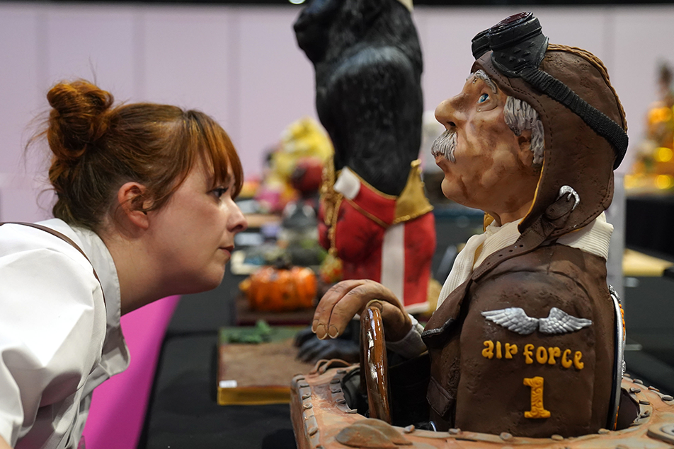 A judge looks at the detail of a cake in the shape of a World War Two pilot depicted sitting in a cockpit