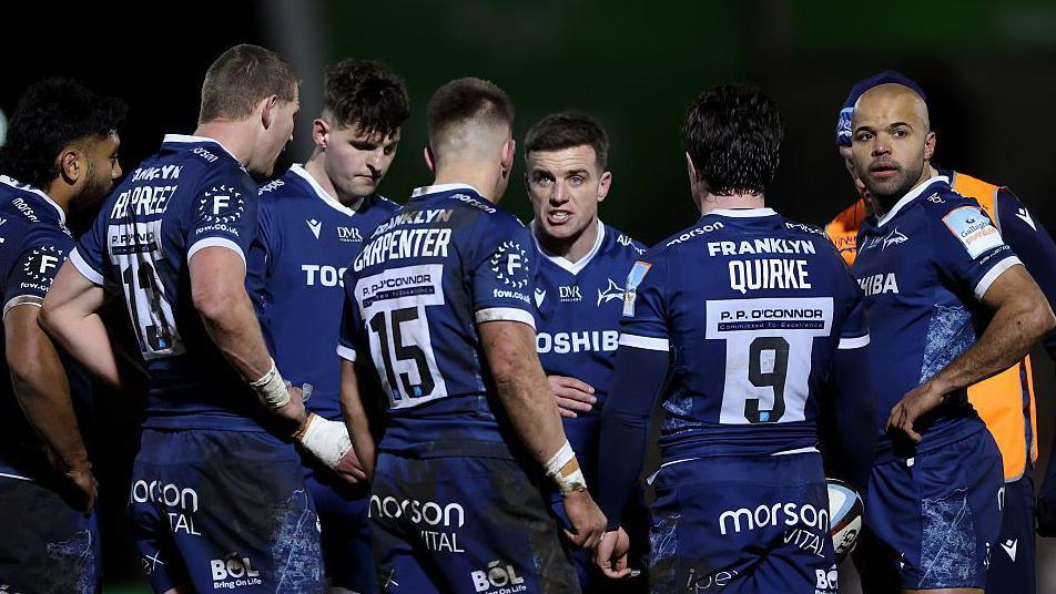 George Ford (centre) stands in a huddle with team-mates and talks