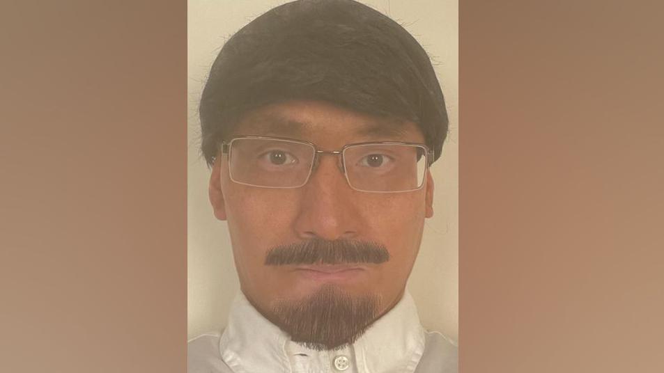 An ID image Kwan took of himself showing him with tanned skin and wearing a fake beard, moustache and wig.