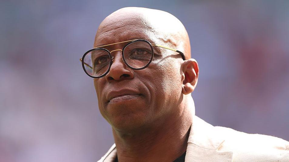 Ian Wright stands on the touchline at Wembley Stadium while conducting punditry for the FA Cup semi final between Manchester City and Nottingham Forest