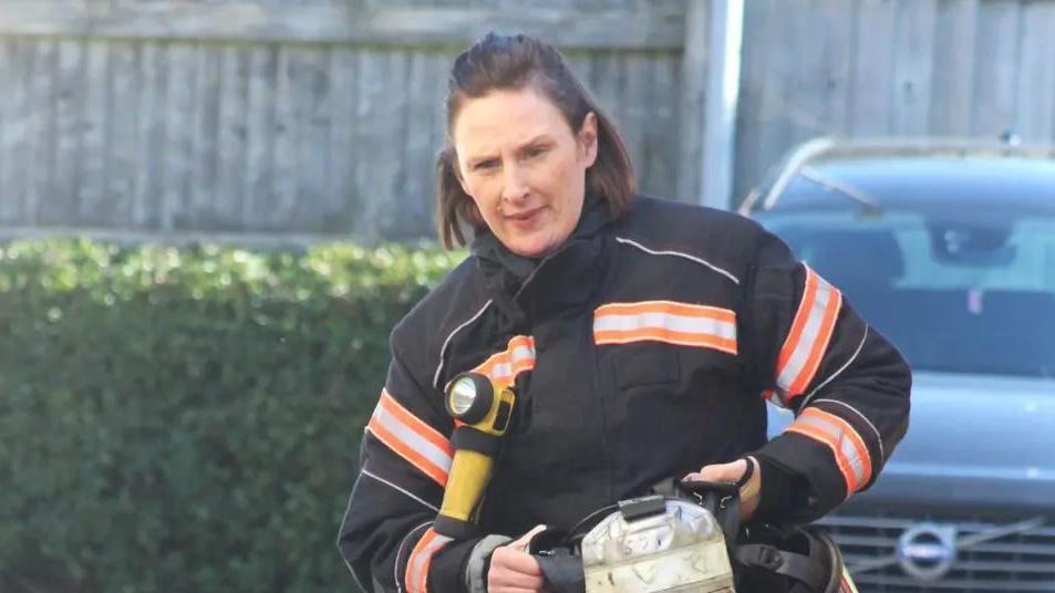 Sonya wearing a white and orange fire-fighter outfit - pic taken while she was walking while looking down.