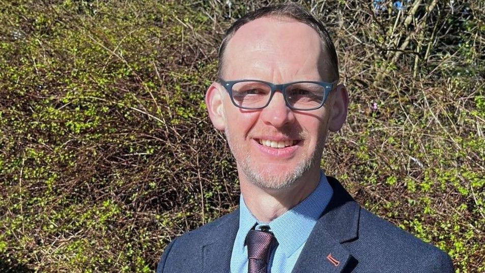 Dr Richard Irvine, chief veterinary officer for Wales, standing in a rural area and smiling at the camera