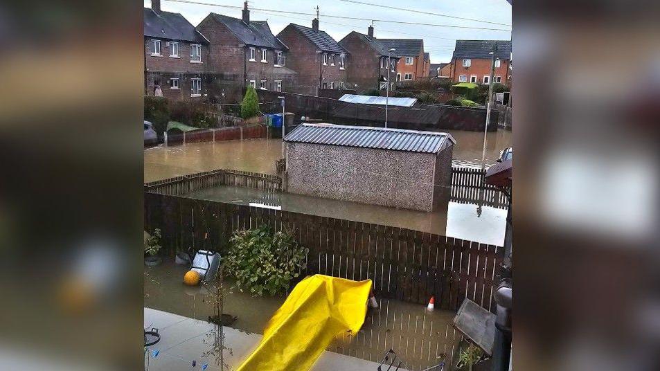 Gardens filled with knee-deep brown water on the Kirkholt housing estate in Rochdale