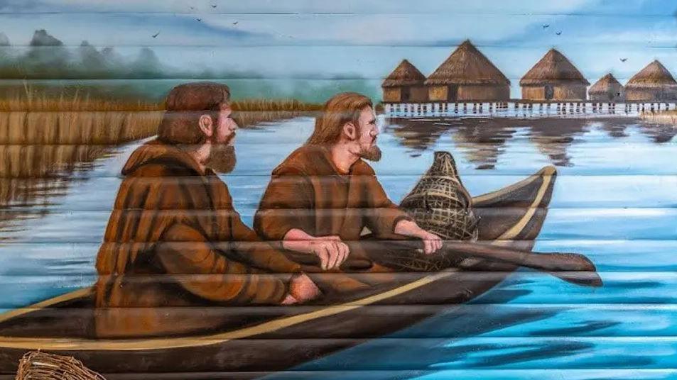 Artist impression of two men in brown rob-like outfits, sitting in a log boats, on the water with round houses in the background.