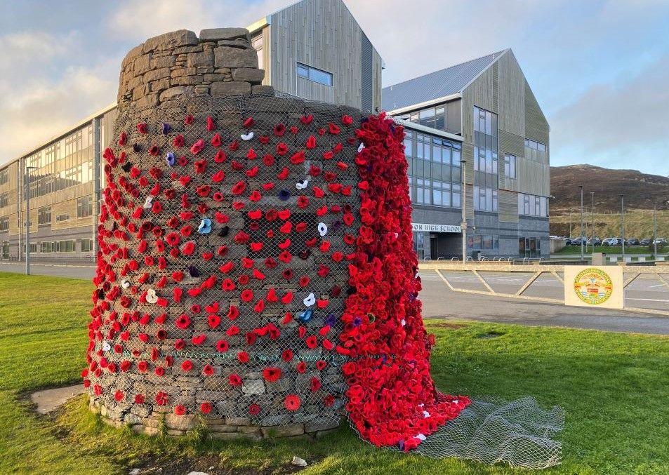 Knitted and crocheted poppies cover a cairn outside Anderson High School.