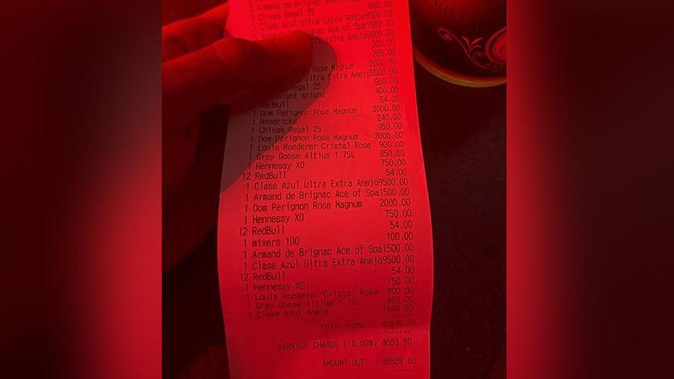 A £88,589.60 bar bill receipt is held in a person's hand.