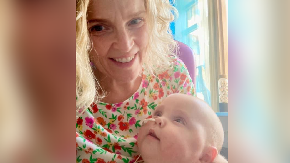 A selfie of Georgina Jones holding her son Osian. Osian is looking up at her and has a tube going into his nose. Ms Jones is smiling looking at the camera. She is wearing a floral top.