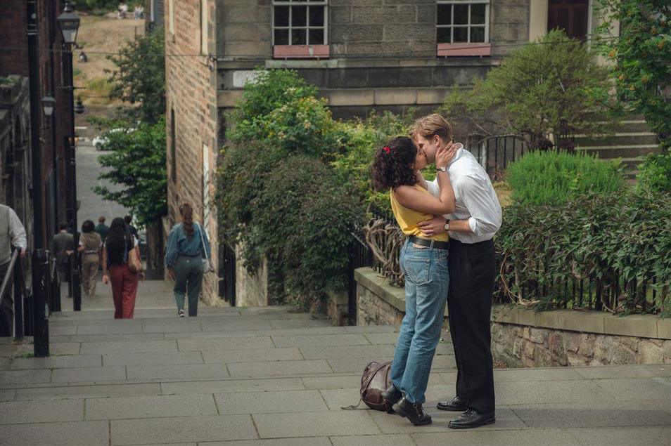 A still image from One Day, showing Emma and Dexter kissing on the steps in The Vennel. 