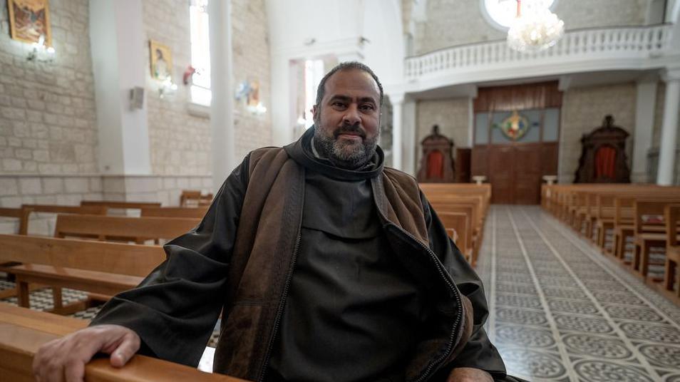 Bearded man sits on a pew in a church