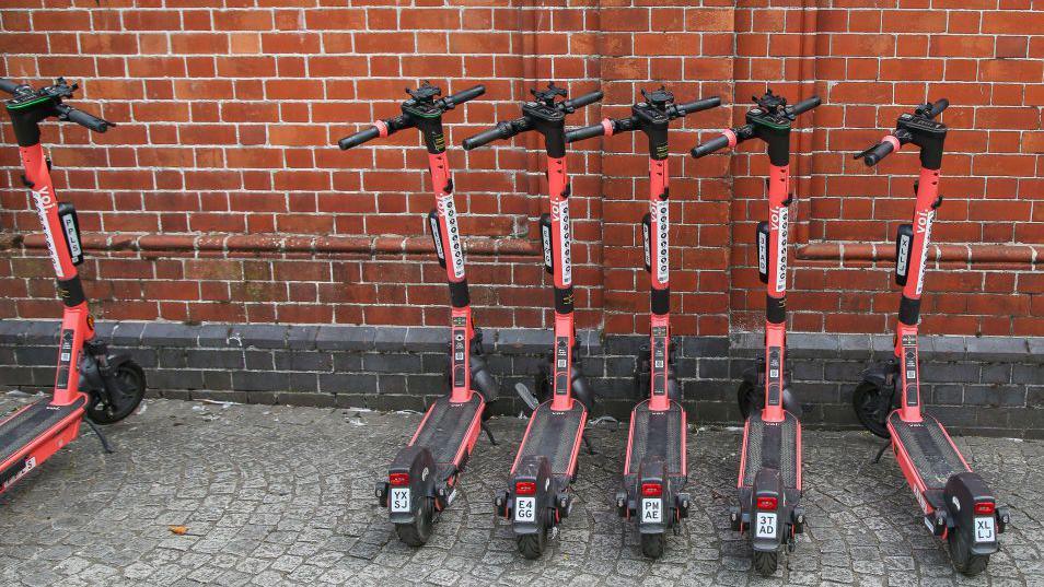 Red electric scooters parked in a line on the pavement in Bristol, England