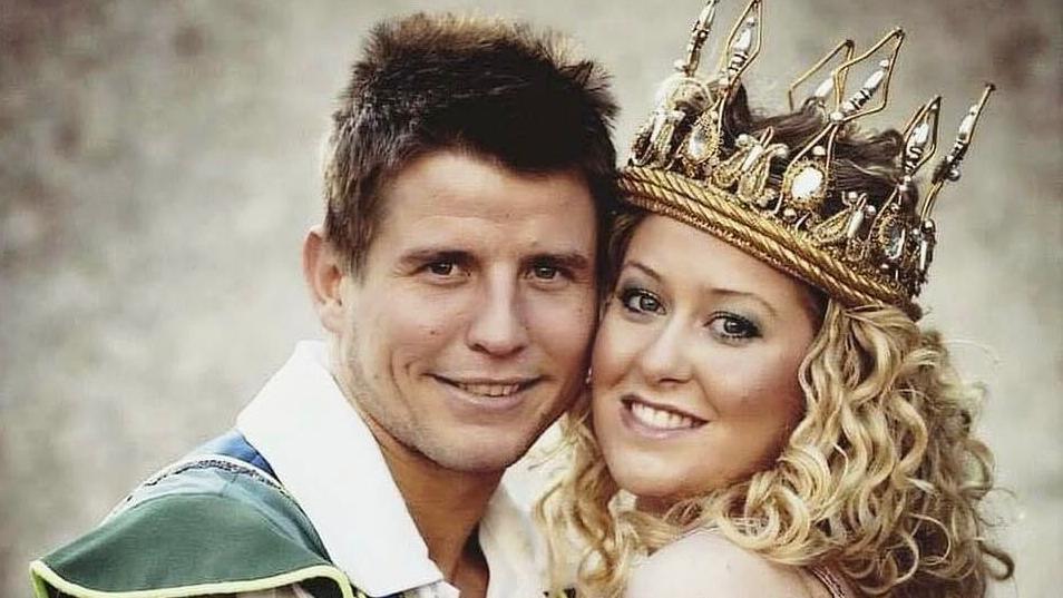 A picture of Graham on the left and Helen on the right in the production of Jack and the Beanstalk. She is wearing a crown and has curly blonde hair. Graham has short brown hair and is wearing a green top with a big white collar.