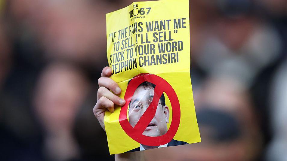 A Sheffield Wednesday fan holds up a sign in protest of owner and chairman Dejphon Chansiri.