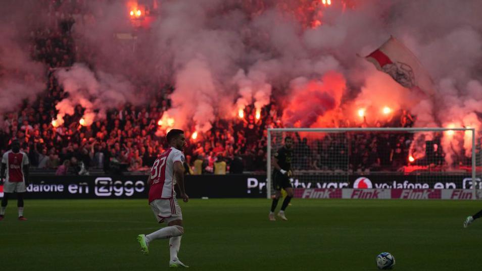 Ajax v Feyenoord match taking place with flares being let off by fans in the stand