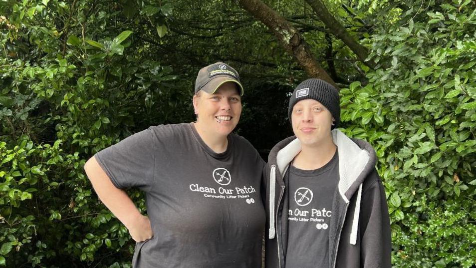 Founders of Clean Our Patch El Clarke and Ash Samuels. Both are standing in front of trees and both are smiling at the camera.