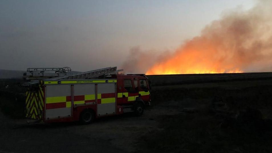 Fire engine with glowing flames in background on horizon