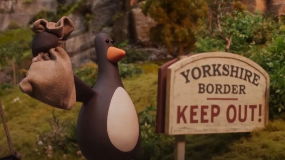 Feather McGraw holds up his booty in a sackcloth bag while next to sign saying "Yorkshire border: Keep Out"